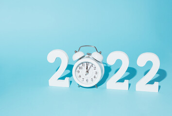 Creative idea made of numbers and a white retro clock as the number 2022, which marks the New Year. Minimal composition on a pastel blue background. Happy New 2022 Year.