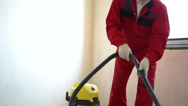 Dust removal with vacuum cleaner. A worker vacuums the floor with an industrial vacuum cleaner. Preparing the floor for tiling. building cleaning service