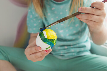 Child paints with watercolors on Easter eggs. Easter eggs festival concept symbolism.