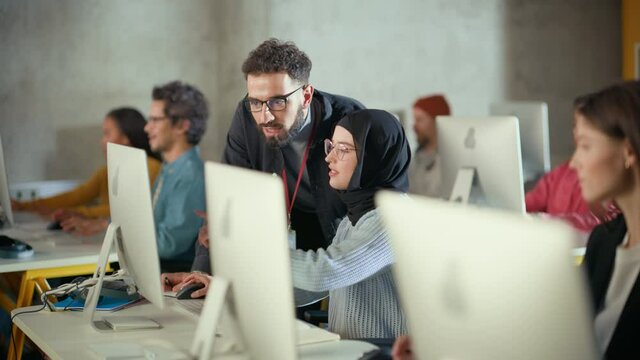 Lecturer Helps Scholar with Project, Advising on Their Work. Teacher Giving Lesson to Diverse Multiethnic Group of Female and Male Students in College Room, Teaching New Academic Skills on a Computer.