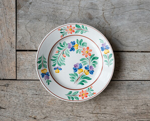 Vintage porcelain plate with folk art flower pattern - on a rustic wooden table