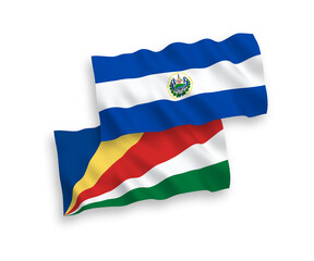 Obraz premium National vector fabric wave flags of Republic of El Salvador and Seychelles isolated on white background. 1 to 2 proportion.