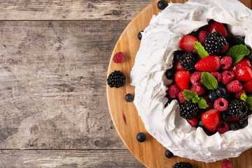 Delicious Pavlova cake with meringue topped and fresh berries on wooden table. Copy space