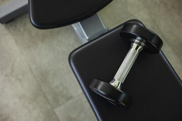 Dumbbell on the bench in modern indoor gym background. Fitness sport club with heavy weight...