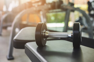 Dumbbell on the bench in modern indoor gym background. Fitness sport club with heavy weight training equipment for Muscular.