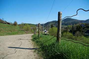 Old fence near the dirt road in the mountain village in Carpathians, Ukraine