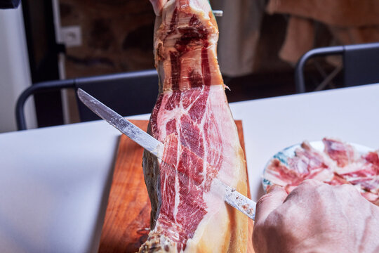 hand of a professional ham cutter cutting an Iberian ham into thin slices ready to eat - Powered by Adobe