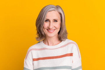 Portrait of attractive cheerful grey-haired woman good mood isolated over vibrant yellow color...