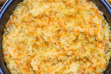 Top view of traditional Italian yellow risotto, closed view forming texture with rice grains, carrot, tomato, onion and green onion.