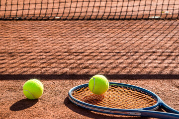 Tennis racket and new tennis ball on a Red clay court.