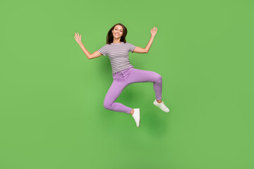Fototapeta na wymiar Full body photo of joyful young positive woman jump up raise hands good mood weekend shopping isolated on green color background