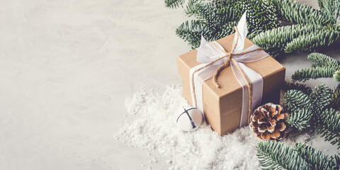 Christmas gift box in the snow on gray background.