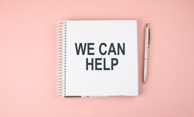 WE CAN HELP text on notebook with pen on the pink background
