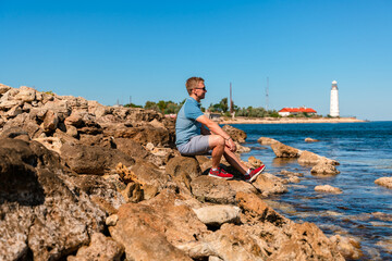 A young man on the Black Sea coast far from the Chersonesos lighthouse. Beautiful summer landscape in Crimea.