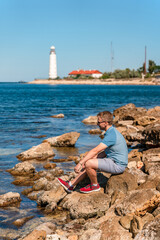 A young man on the Black Sea coast far from the Chersonesos lighthouse. Beautiful summer landscape in Crimea.