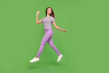 Full length body size view of attractive cheerful girl jumping going waving hi isolated over bright green color background