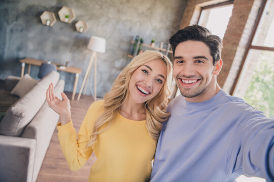 Self-portrait of attractive cheerful couple spending vacation weekend hugging at home loft industrial interior indoors
