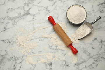 Fototapeta na wymiar Rolling pin and flour on white marble table, flat lay. Space for text