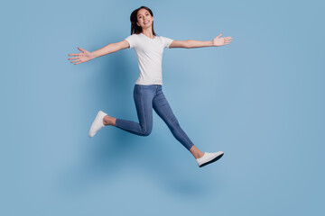 Fototapeta na wymiar Portrait of dreamy nice attractive lady jump run hands wings enjoy free time on blue background