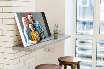 Photo printed on canvas, white background. Happy young family in Santa hats celebrating Christmas at home