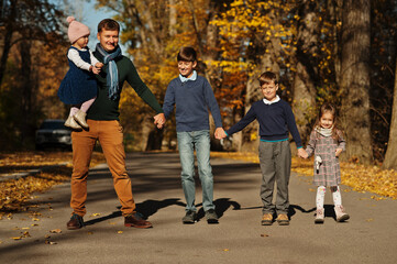 Naklejka na ściany i meble Father with four kids at autumn park.