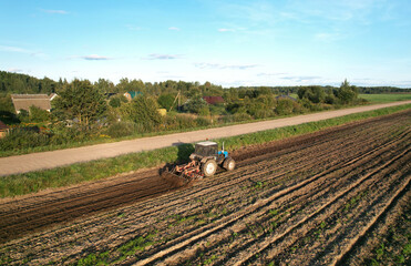Tractor with Plough on Plowed. Ploughing and Soil Tillage. Agricultural Tractor on Cultivation Field for Sowing Seeds. Tractor During Field Cultivating. Planting and Seeding Equipment.