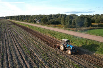 Tractor with Plough on Plowed. Ploughing and Soil Tillage. Agricultural Tractor on Cultivation Field for Sowing Seeds. Tractor During Field Cultivating. Planting and Seeding Equipment.