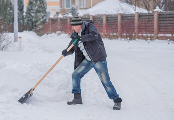 Winter, people and snow problem concept - man digging snow with shovel at yard. Man standing with...