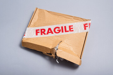 Broken fragile parcel, torn cardboard box on office desk