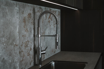 Modern dark grey kitchen design - detail of interior with steel faucet.