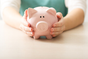 Obraz na płótnie Canvas woman hand putting money coin into piggy for saving money wealth and financial concept