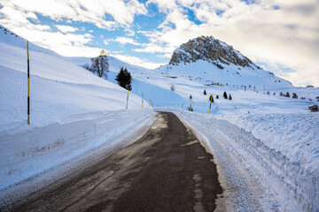 Deserted high altitude alpine pass road cleared of snow on partly cloudy winter day
