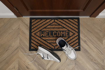 Stylish shoes near door mat in hall, top view