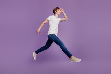 Fototapeta na wymiar Full body profile side photo of young cheerful man jump walk look ahead forward isolated on violet color background