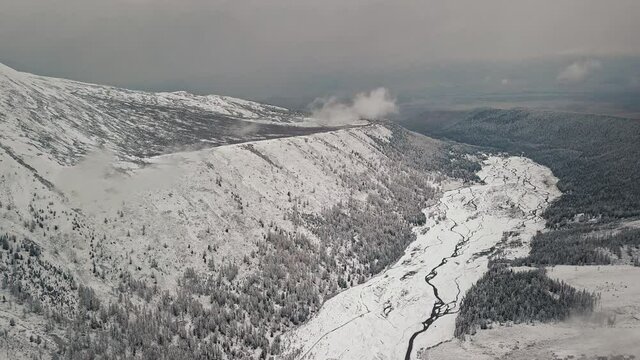 Storm, snowfall in the huge glacier of Mount Belukha, the valley of the Aktru River, the Altai Mountains. Cloudy weather, stone in the snow, storm, wildlife, winter forest, frozen mountain river in