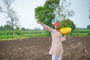 Indian farmer spreading fertilizer in the agriculture field.