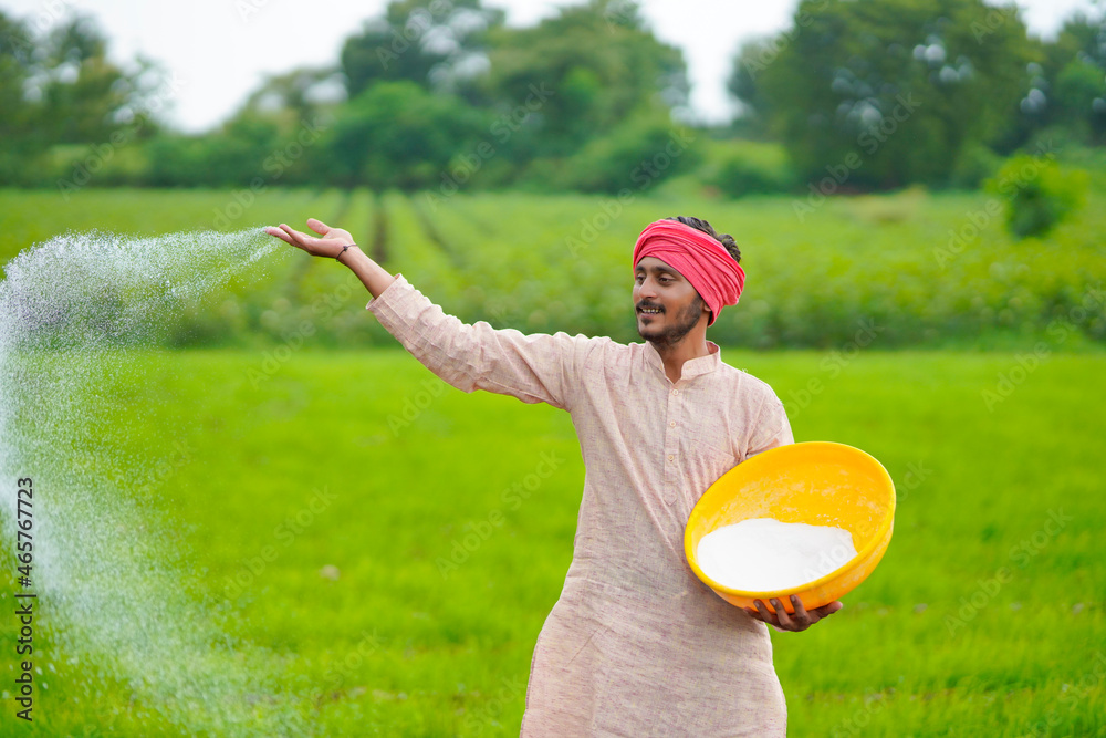 Sticker Indian farmer spreading fertilizer in the agriculture field.