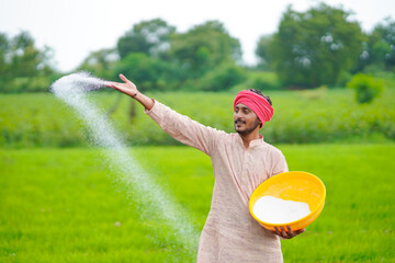 Indian farmer spreading fertilizer in the agriculture field.