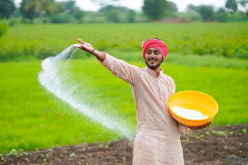 Indian farmer spreading fertilizer in the agriculture field.
