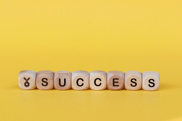 Wooden cube with the word SUCCESS on yellow background. Business success concept.