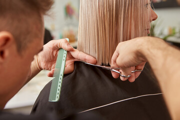 Hairdresser hands cutting woman hair in beauty salon