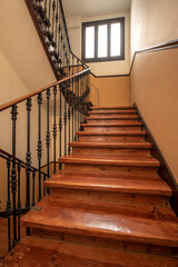 Vintage wooden stairs and wrought iron railing in old and central building