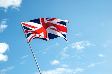 Great Britain England flag waving in the wind over cloudy grey sky low angle view close up.