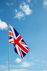 Great Britain England flag waving in the wind over cloudy grey sky low angle view close up.