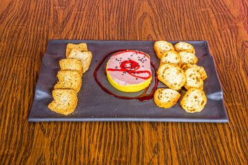 Portion of foie with jam and toasts on wooden table