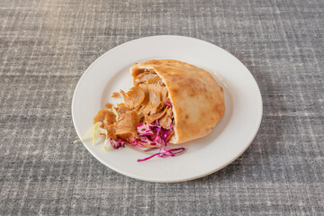 Sliced grilled lamb doner kebab sandwich with onion, purple cabbage, lettuce and tomato with yogurt sauce on gray table