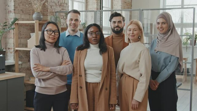 Portrait shot of diverse group of office workers posing for camera in office