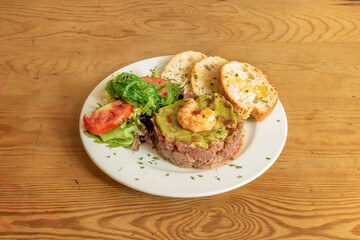 Red tuna tartare with guacamole, prawns, wakame seaweed and salad with lettuce and tomato