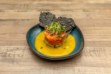 Norwegian salmon tartare with a base layer of zucchini, pumpkin cream and crunchy black biscuit