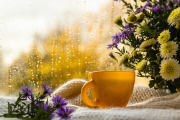 Yellow cup with hot green tea on a white knitted blanket on a rainy autumn day. Autumn mood.